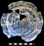 White refined earthenware small plate printed underglaze in medium blue in the Castle and Bridge pattern (Coysh and Henrywood 1982:73).  This pattern may represent a view of St. Albans Abbey, Hertfordshire and has been found with the marks of Henshall, Williamson & Co. Henshall & Co. (1790 – 1828), Longport.  This vessel is unmarked. 6.50” rim diameter.